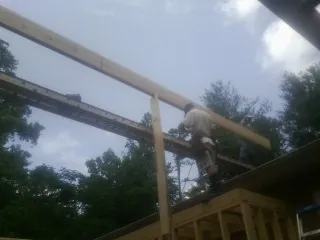Carpenter setting a ridge beam over a new addition frame — Ice Dam Removal by Roofing Brothers in State Center