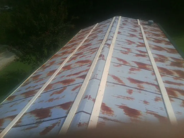 Rusted metal roof panels with new wood purlins before replacement — Storm Damage Roof Repair in State Center by Roofing Brothers