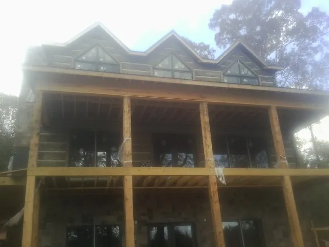 Dormers and porch framing on a large log home under construction — Roof Coating work by our crew in State Center