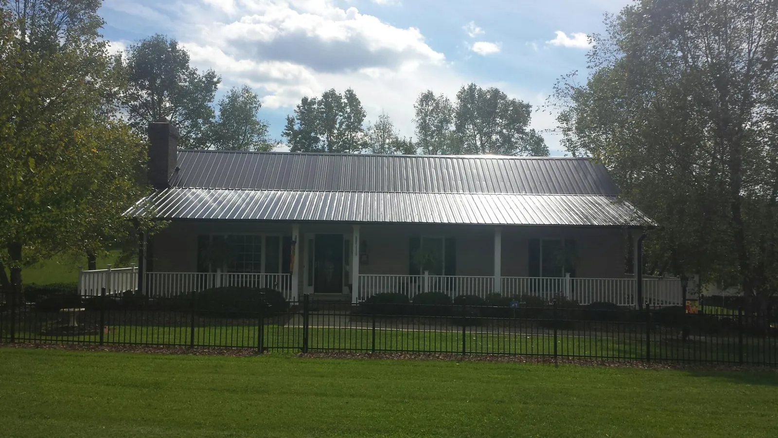 Gray metal roof on a brick ranch with a full width front porch — Gutter Guard Installation work by our crew in State Center