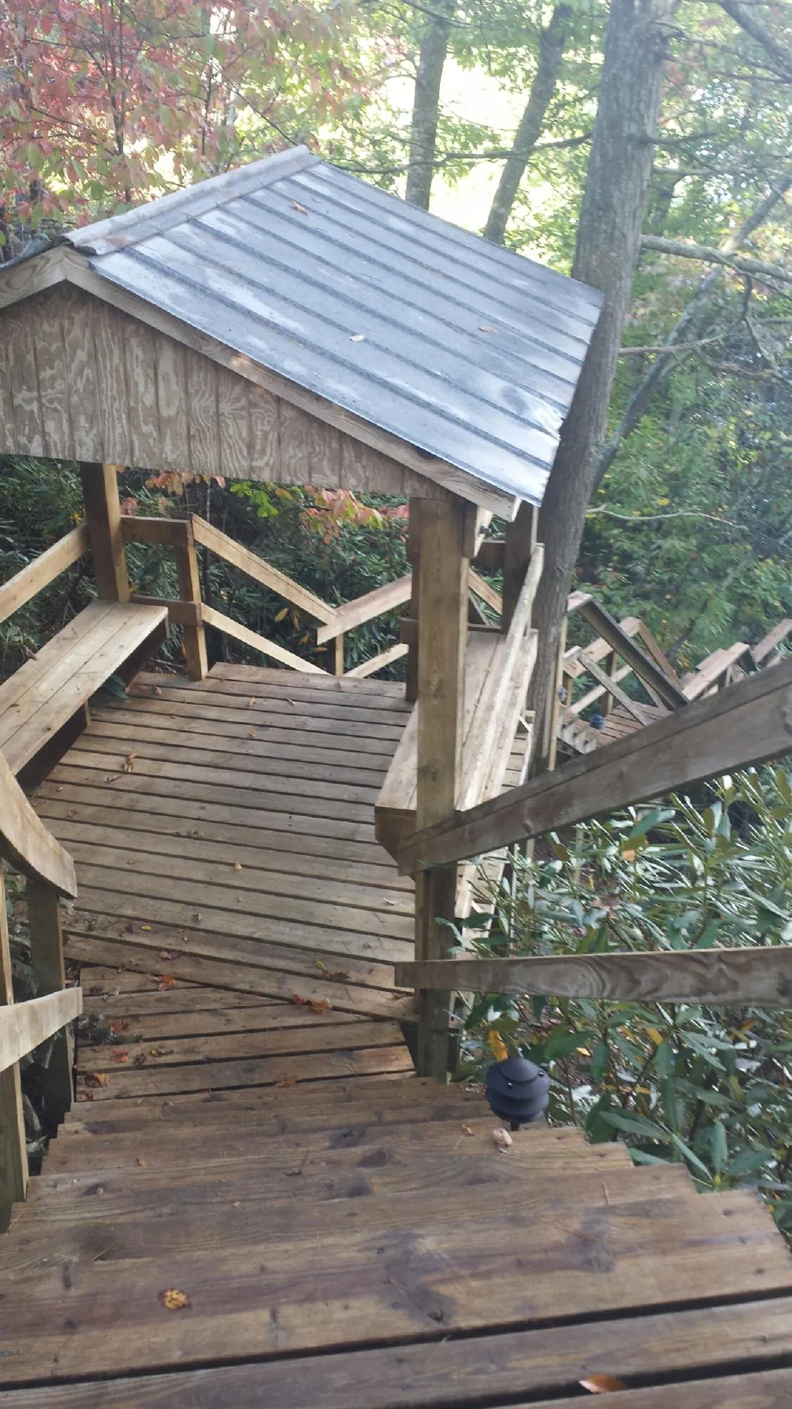 Metal roofed shelter over wooden steps on a wooded walkway — Skylight Repair & Installation work by our crew in State Center