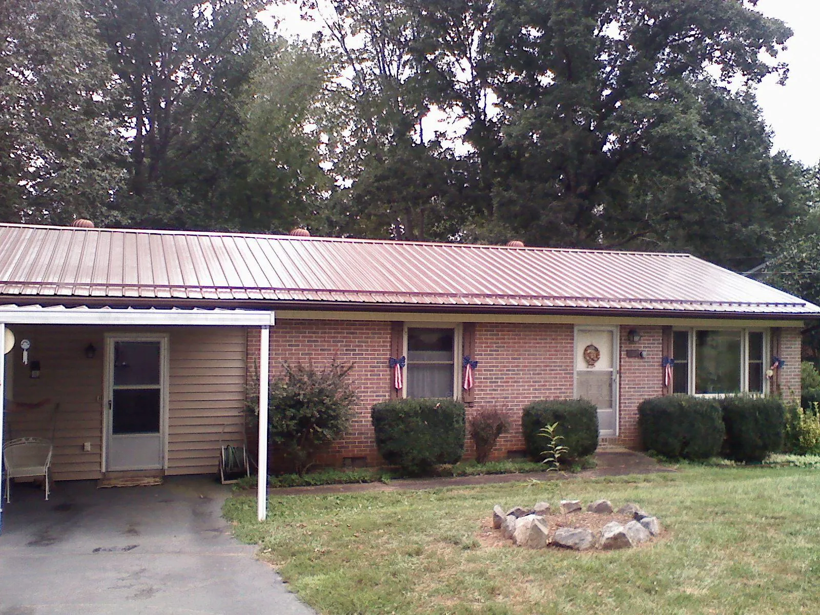Bronze metal roof and carport on a brick ranch home — Roof Repair work by our crew in State Center