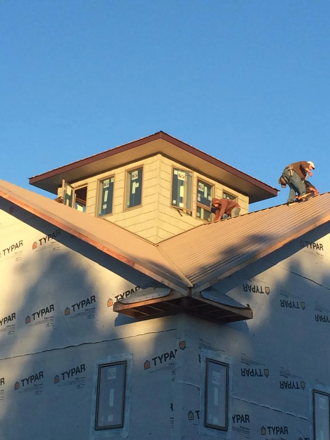 Roofers working around a rooftop cupola on a new metal roof at sunset — Roof Waterproofing in State Center by Roofing Brothers